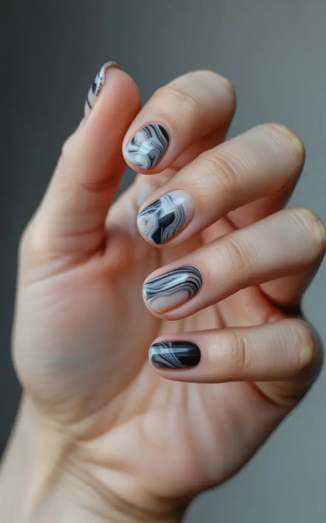 Full closeup to female hands with marble effect nails featuring black and white swirled patterns, natural stone texture design, artistic water marble technique, elegant hand pose, sophisticated manicure.