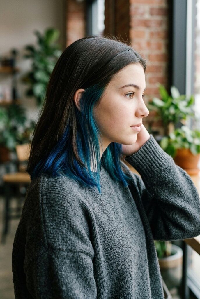 Teen girl with a bold peekaboo underlayer color peeking beneath natural hair Teen girl with a bold peekaboo underlayer color peeking beneath natural hair