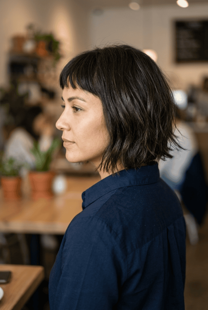 Woman with textured French bob and micro bangs shown from the side
