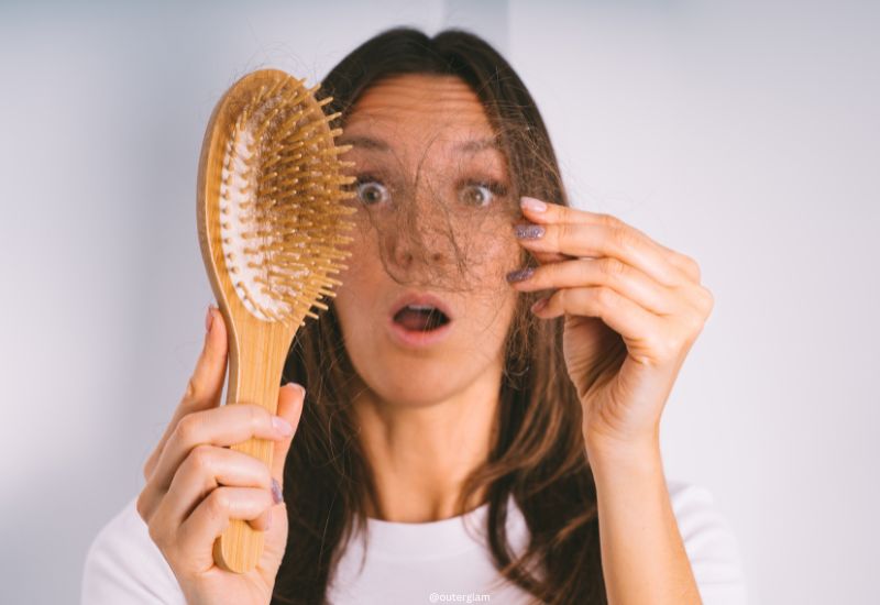 Young woman shocked because of hair loss problem. Woman holding hair brush and showing damaged hair. Bad hair falling out